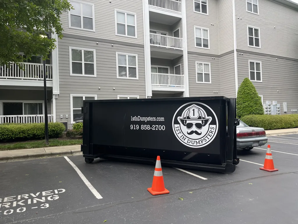 1st In Dumpsters roll off dumpster with safety cones in an apartment parking lot