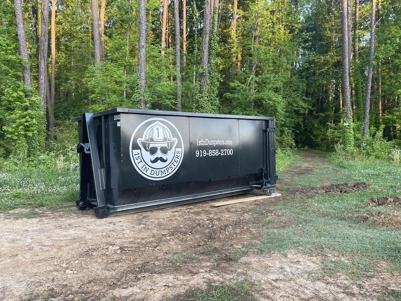 1st In Dumpsters roll off dumpster on a wooded residential lot